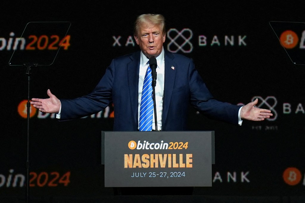 Президент Дональд Трамп жестикулює на заході Bitcoin 2024 в Нешвіллі, штат Теннессі, стоячи на подіумі.