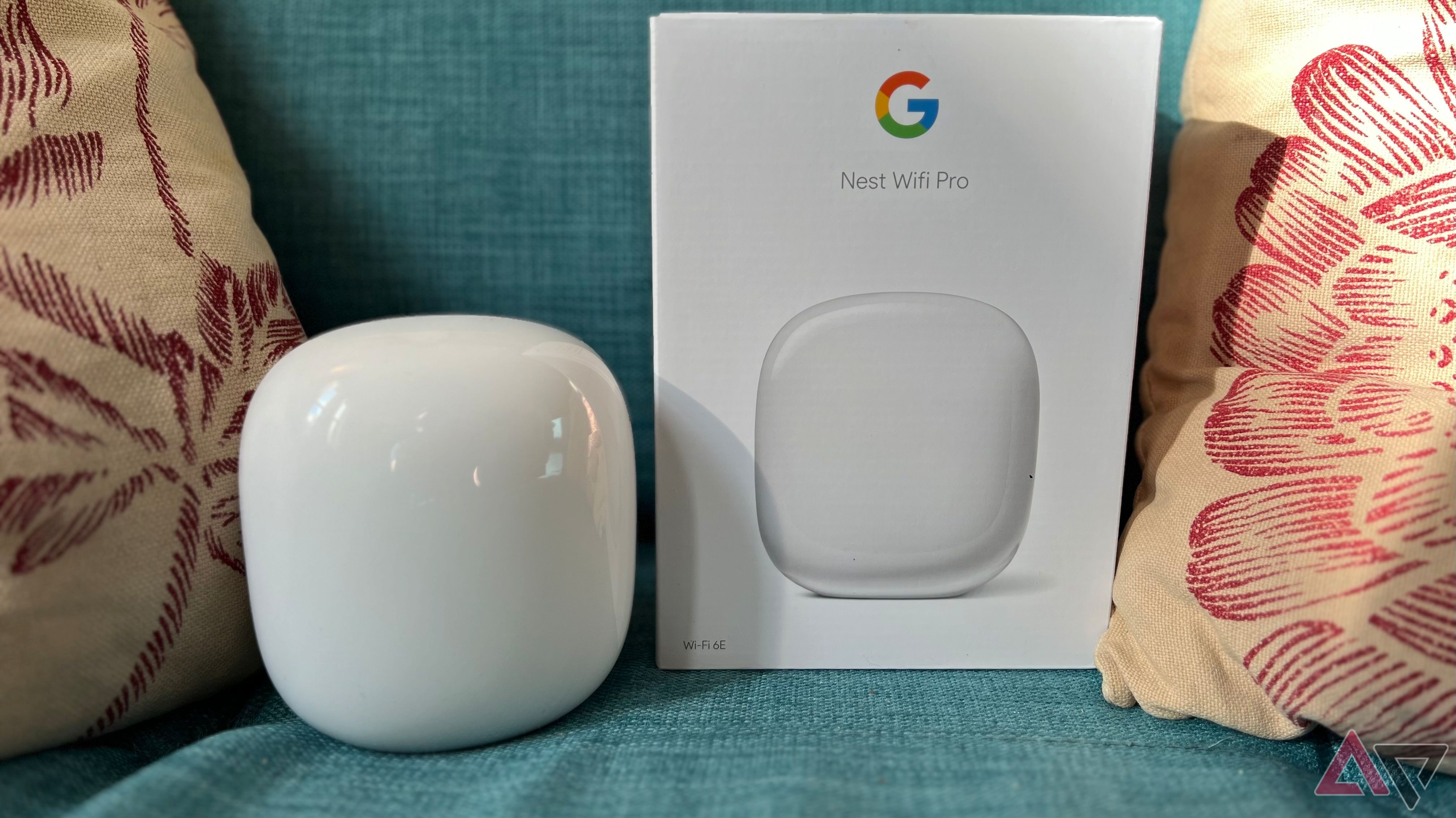 Google Nest Wi -Fi Pro з коробкою на дивані, оточеному подушками