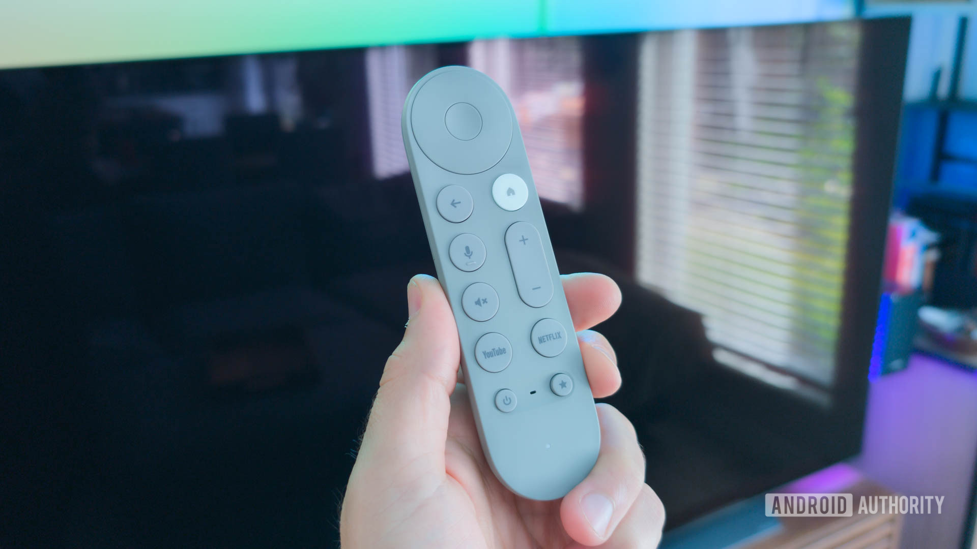 Google TV Streamer віддалений у руці перед порожнім телевізором