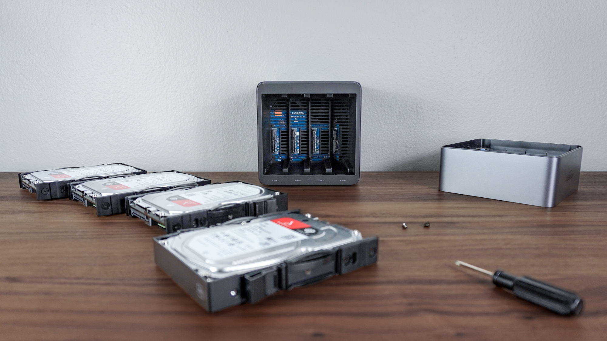 Встановлення чотирьох жорстких дисків у Ugreen NASync DH4300 Plus із усіма ними та різними деталями, необхідними для цього, на столі