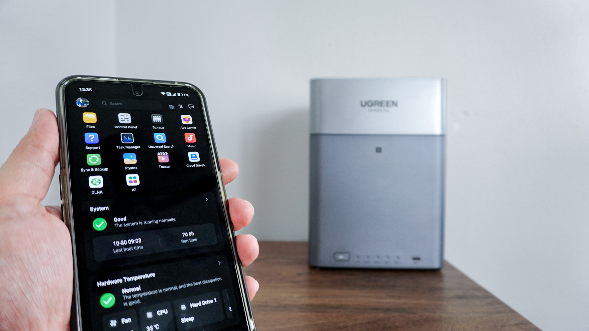 Людина, яка використовує програму Ugreen NAS на своєму телефоні з Ugreen NASync DH4300 Plus у фоновому режимі